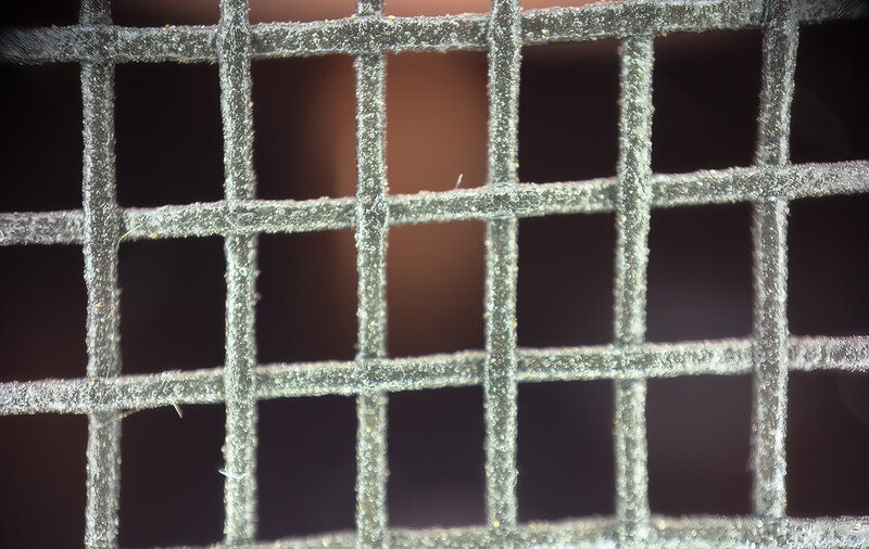 Frost-covered window grid creating geometric patterns of crystalline ice against dark interior background.