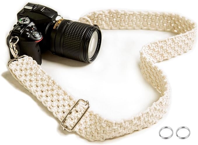 Black DSLR camera with telephoto lens attached to a cream-colored woven camera strap.