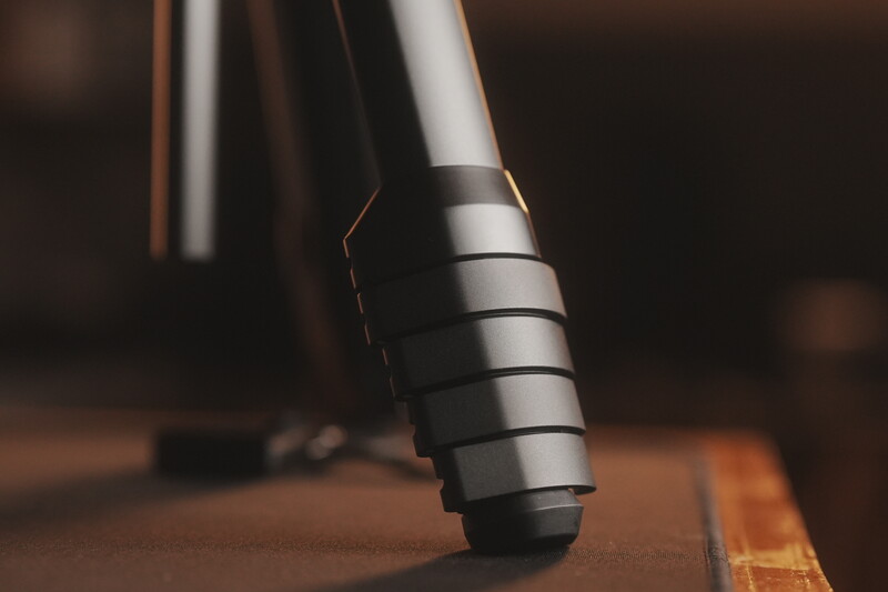 Close-up of a telephoto lens with stacked extension rings mounted on a wooden surface.