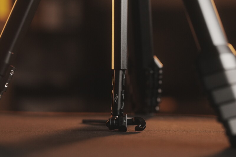 Close-up of a bicycle fork and front wheel on a wooden floor with studio lighting.