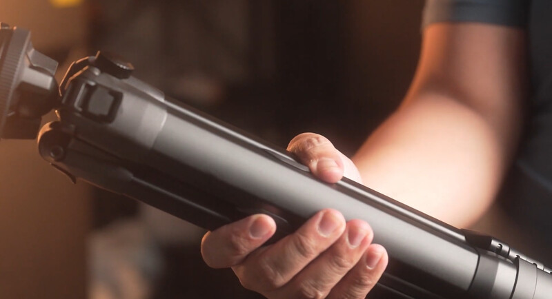 Photographer holding a telephoto lens with warm golden hour lighting in the background.