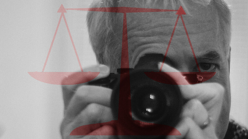 Photographer holding camera with scales of justice overlay in red.