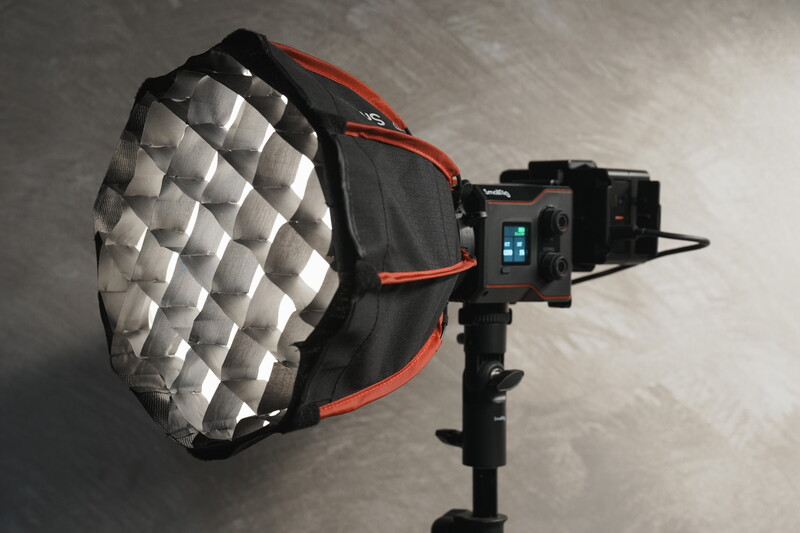 Studio lighting fixture with large silver parabolic softbox and red frame mounted on stand with control panel.