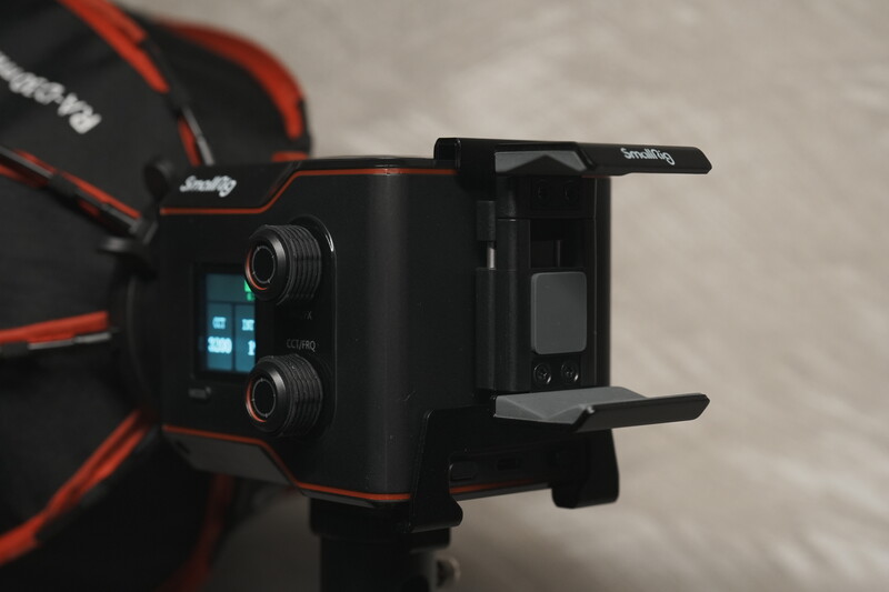 Black compact camera rig with red accents and dual lens setup mounted on articulating arms.