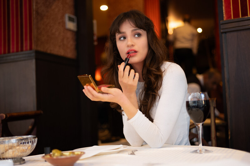 Model applying makeup in a Paris cafe.