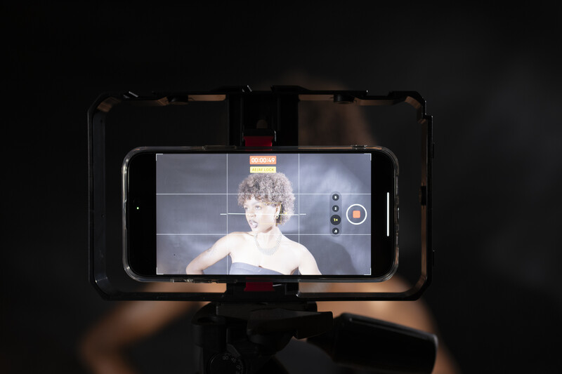 Smartphone mounted on a rig displaying a woman's face in portrait orientation during video recording.