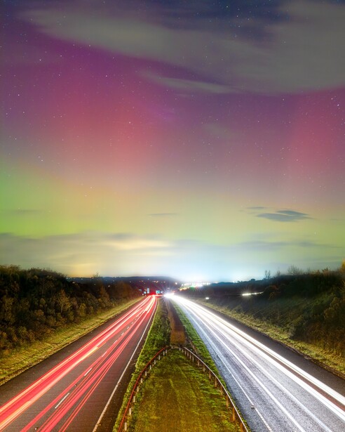 Highway at dusk with light trails from vehicles stretching toward the horizon beneath a gradient sky.