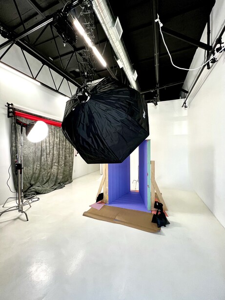 Professional photography studio setup with softbox lighting, blue seamless backdrop, and white cyclorama floor.