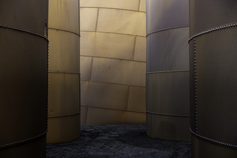 Interior view of three large cylindrical metal tanks with riveted seams in an industrial space.