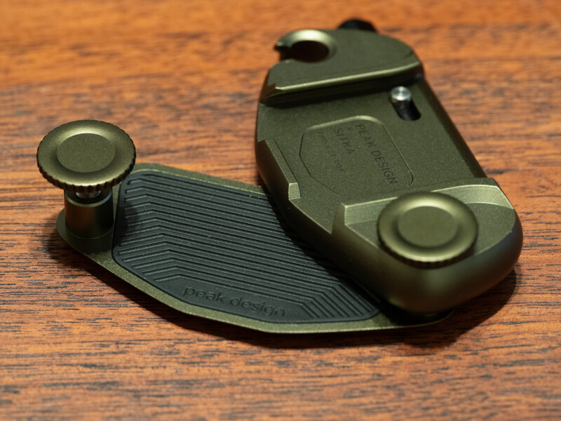 Green gaming controller with detachable joystick module and curved grip base on wooden surface.