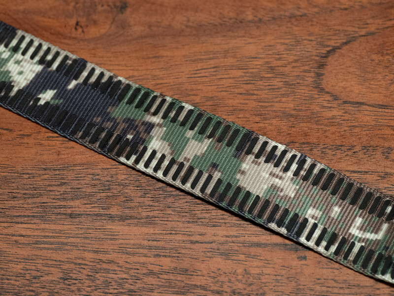 Woven lanyard with piano keyboard and musical note pattern on dark wood surface.