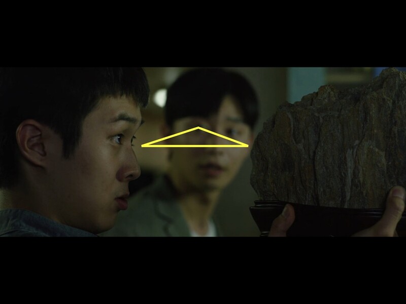 Screenshot from a film showing a young man in profile with a neon yellow triangle overlay on his face.