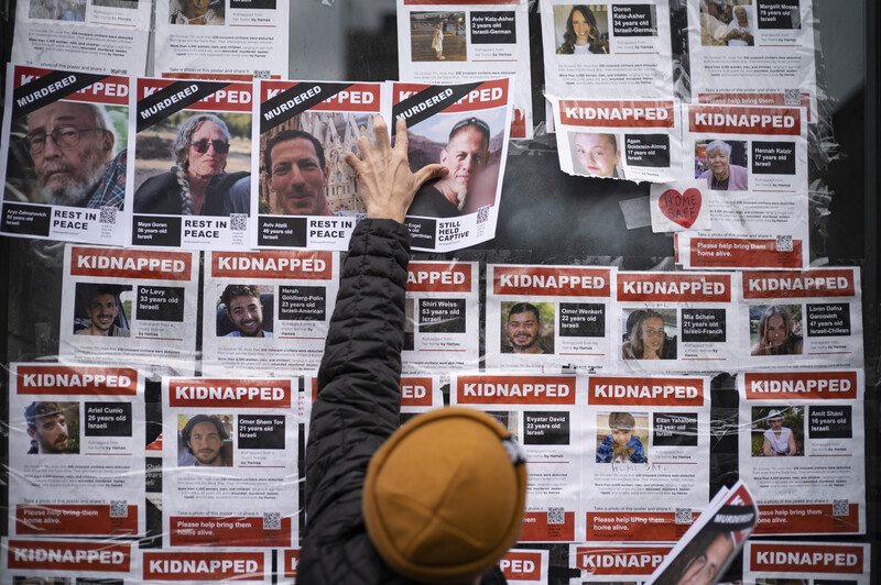 Person in yellow hat viewing wall covered with kidnapping awareness posters and flyers.