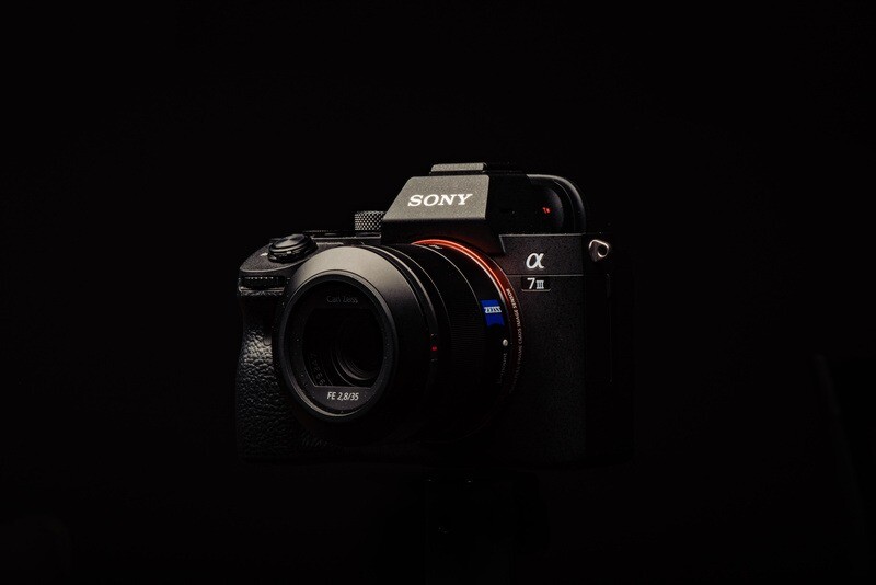 Sony α7 II mirrorless camera with attached lens against black background.