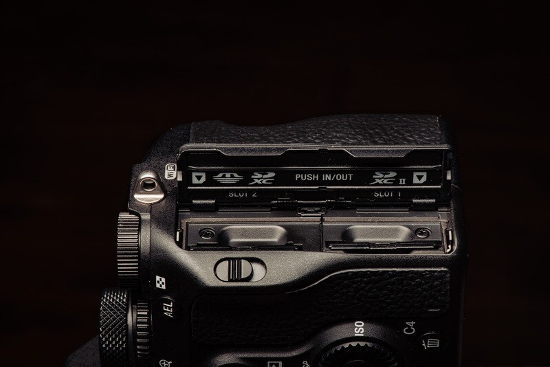 Close-up of a camera's film advance mechanism and shutter button against a dark background.