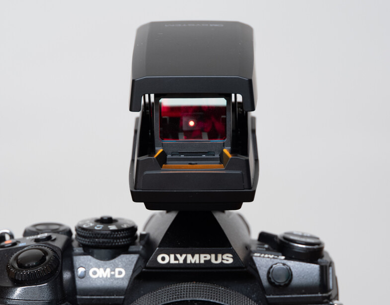 Olympus OM-D camera with open electronic viewfinder attachment mounted on top.