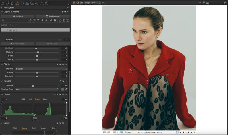 Woman in red blazer with patterned teal sweater, photographed against neutral background in editing software.