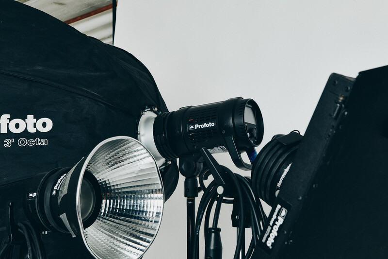 Professional studio lighting setup featuring a Profoto monolight with reflector and mounted light modifier.