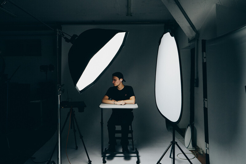 Photographer sitting at a desk in a studio lit by two large oval softboxes positioned on either side.