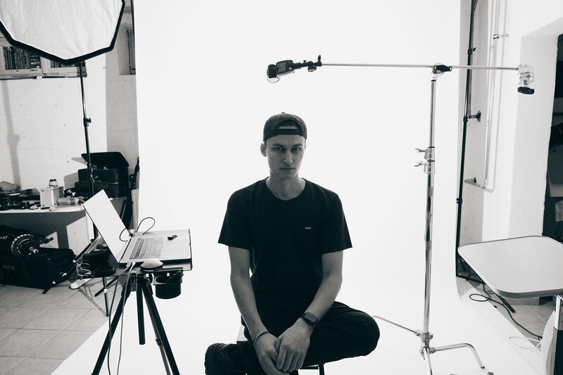 Photographer sitting in a professional studio setup with camera on tripod and professional lighting rigs.