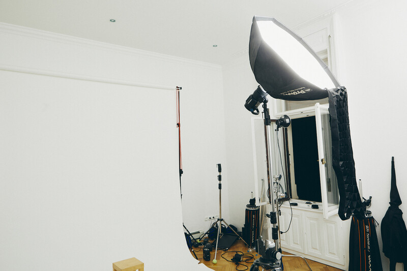 Professional photography studio setup with softbox and lighting equipment mounted on stands against white walls.