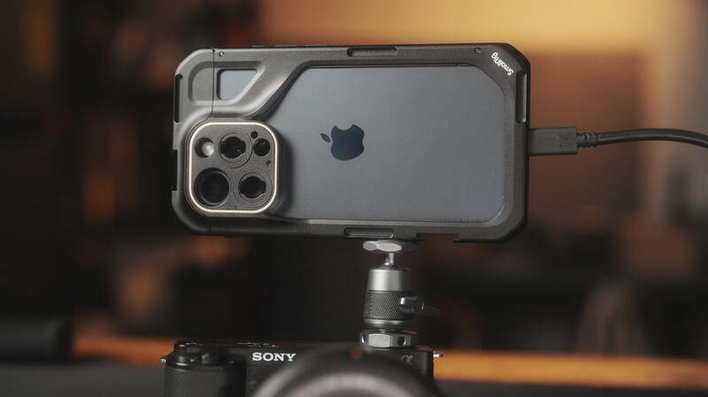 iPhone mounted on a tripod head with a protective case and external lens attachment.