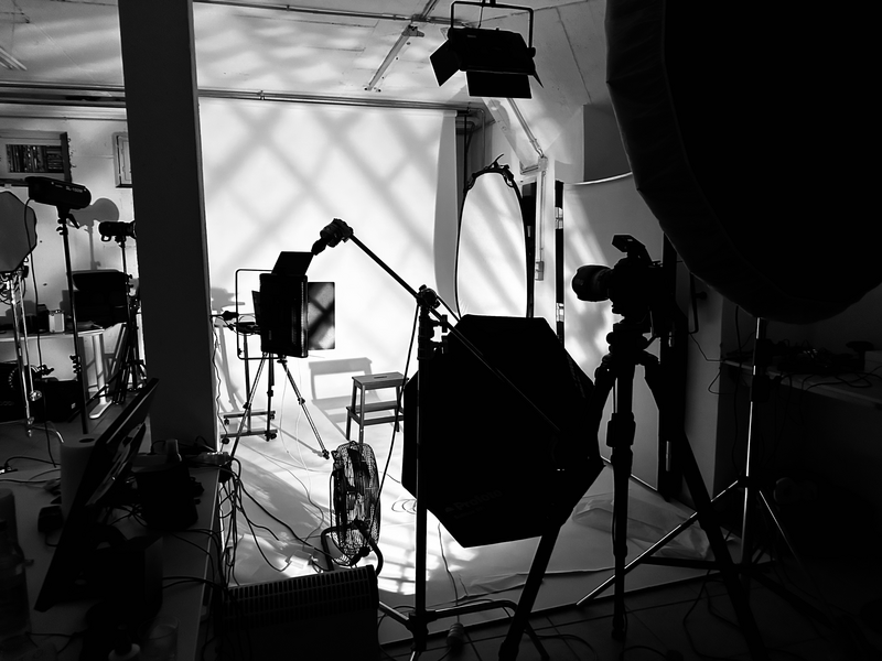 Professional studio lighting setup with silhouetted equipment and softbox, backlit by window light.