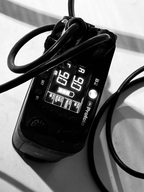 Black vintage rotary telephone with coiled cord photographed from above in high-contrast black and white.