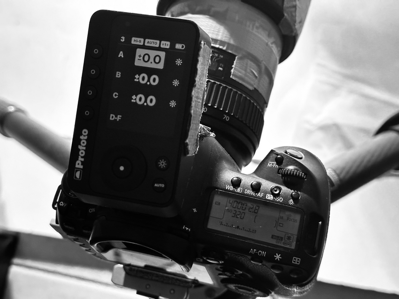 Photographer holding light meter and camera displaying exposure readings against cloudy sky.