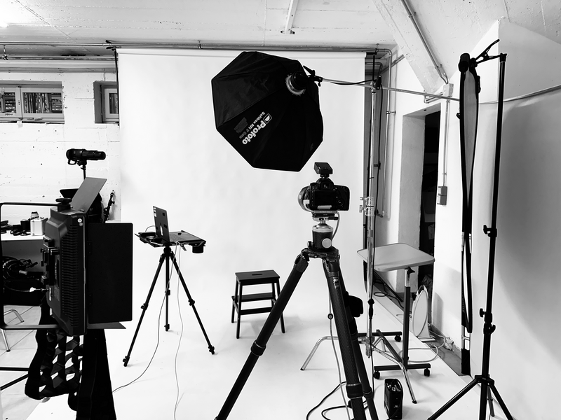 Professional studio setup with camera on tripod, large octagonal softbox, and lighting equipment in white-walled space.
