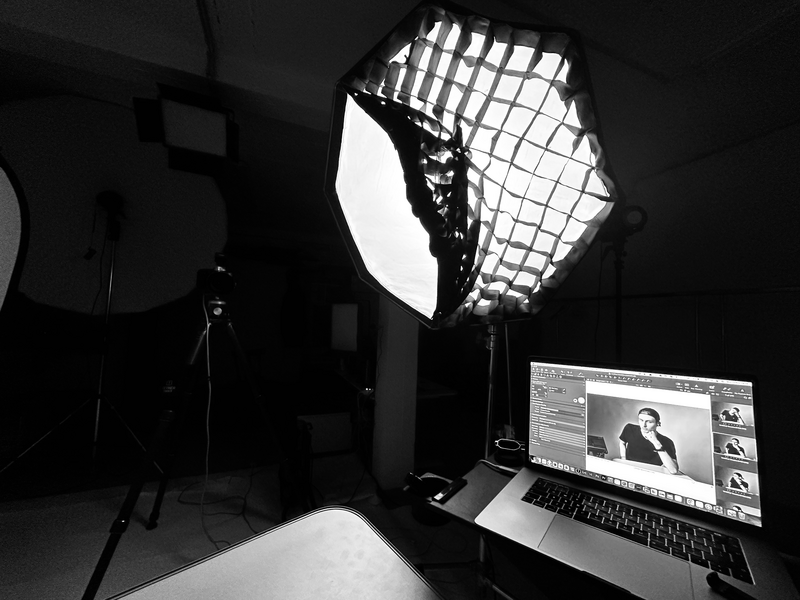 Professional studio setup with large octagonal softbox and laptop displaying photo editing software.
