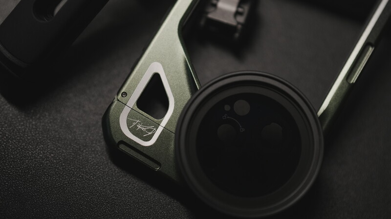 Close-up of a smartphone with a wide-angle lens attachment on a dark surface.