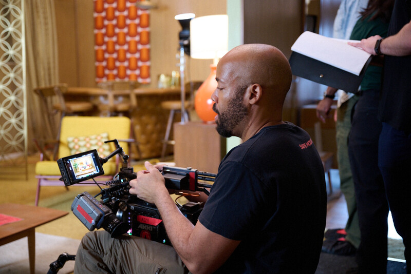 Cinematographer operating a compact cinema camera rig with external monitor and follow focus system on set.