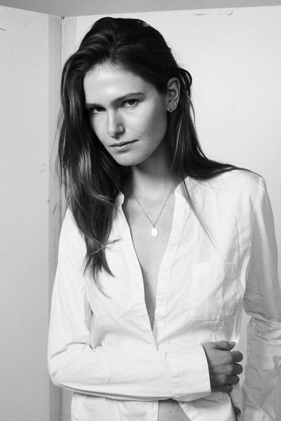 Woman in white button-up shirt against white background in black and white portrait.