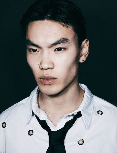 Portrait of an Asian man with dark hair wearing a white button-up shirt over a black v-neck shirt.