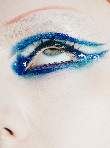 Close-up of an eye with bold blue eyeshadow and graphic winged eyeliner design.