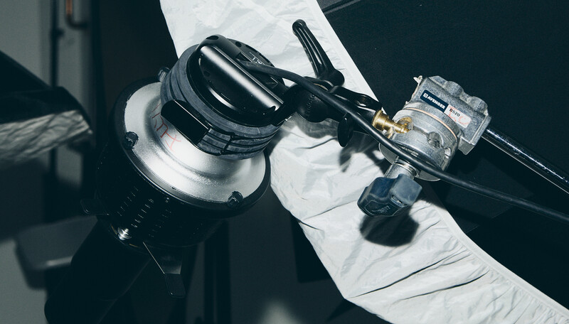 Close-up of camera flash and light meter held in gloved hands against dark background.