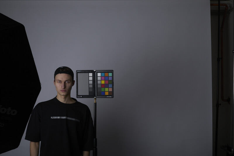 Portrait of a person next to a color checker card mounted on a studio light stand.