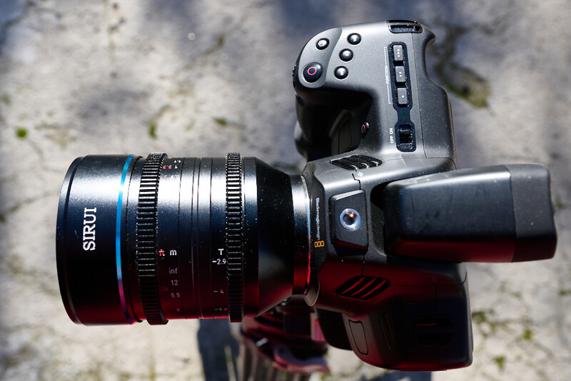 Mirrorless camera with Sirui cinema lens mounted on weathered concrete surface.