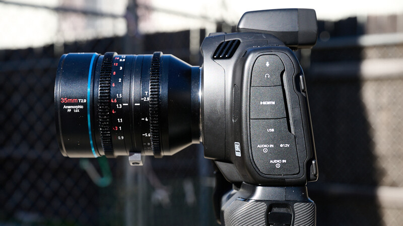 Cinema camera with manual focus lens mounted, showing control panel and connectors on right side.
