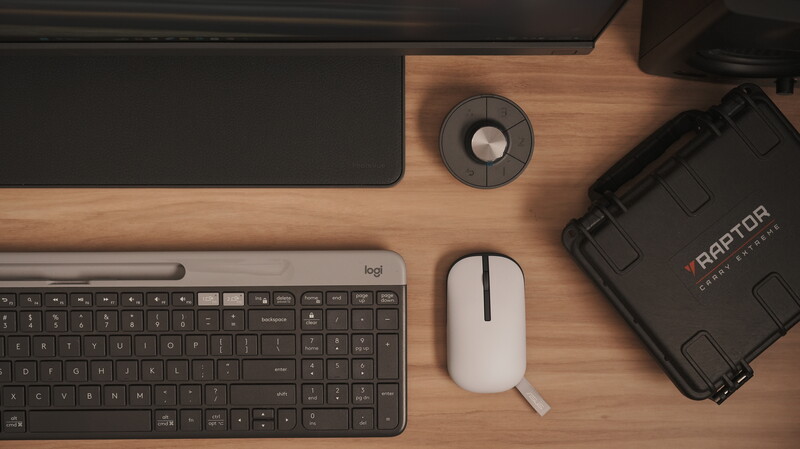 Flat lay of a photographer's desk setup with keyboard, mouse, and equipment case on wooden surface.