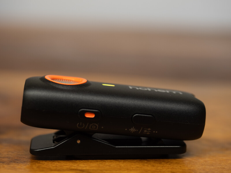 Black camera remote trigger with orange accents mounted on a wooden surface.