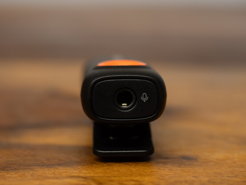 Compact black webcam with orange accent strip positioned on wooden surface.