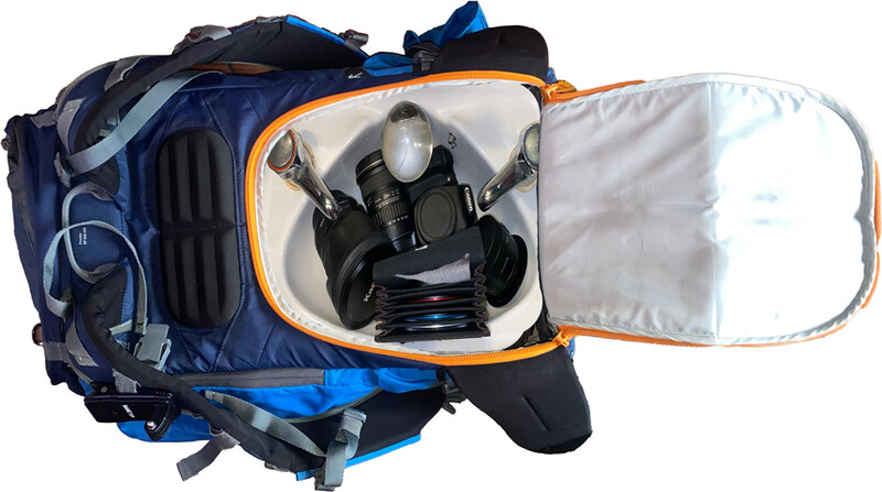 Blue and black camera backpack with an open compartment displaying a gas mask and protective gear.