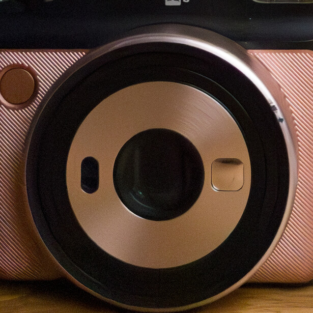 Pink instant camera with dual lens setup and black accents, viewed from above.
