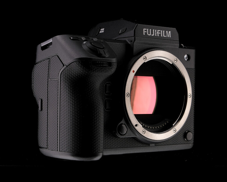 Fujifilm medium format camera body with open mirror box and pink sensor visible against black background.