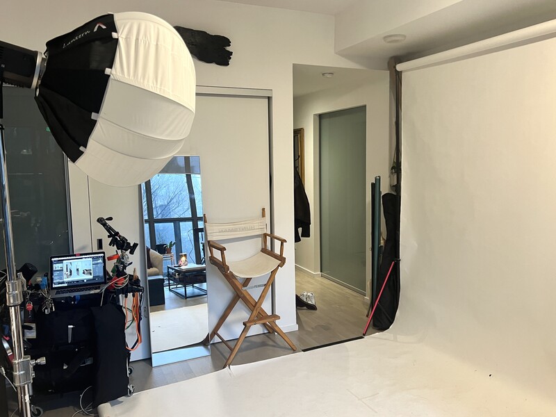 Professional photography studio setup with large softbox, director's chair, and white seamless backdrop.