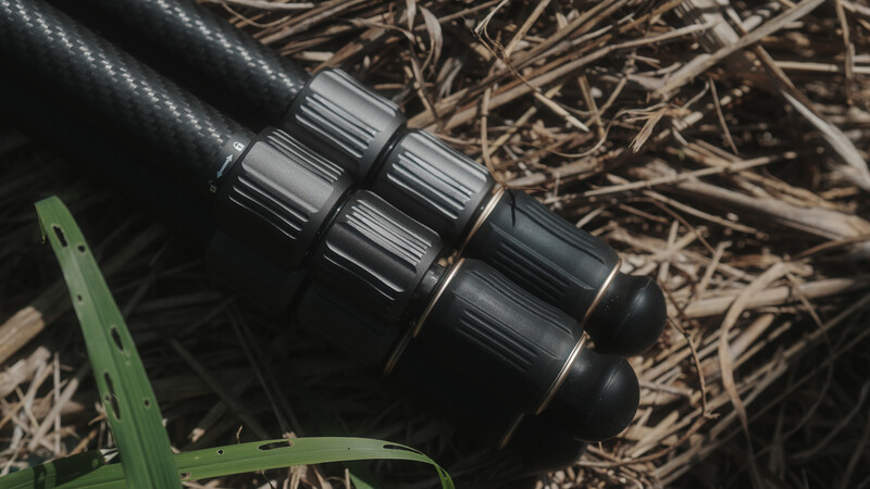 Close-up of a tactical shotgun shell holder mounted on a rifle with dry grass in background.