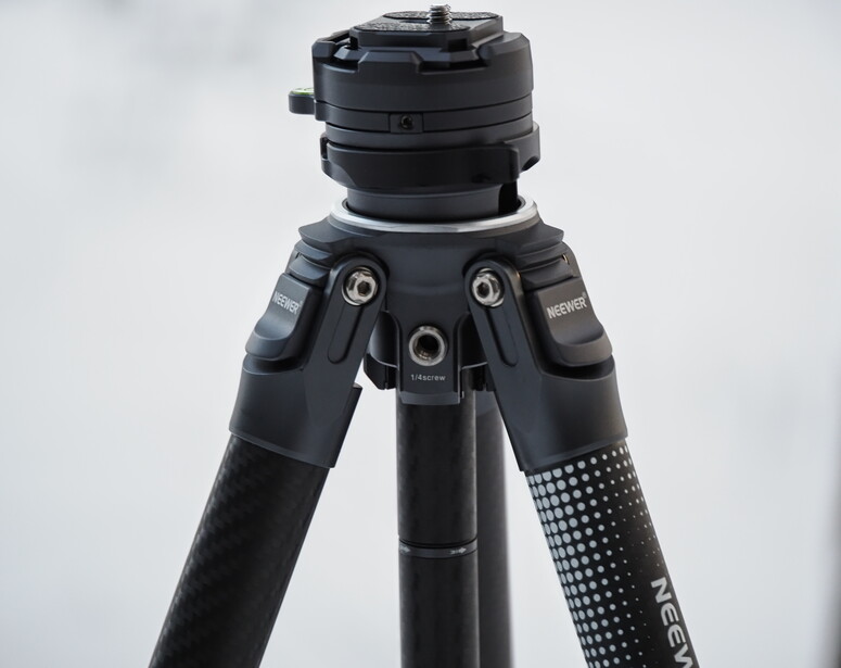 Professional tripod with black carbon fiber legs and ball head against white background.