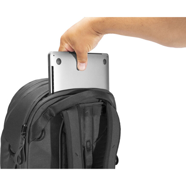 Hand placing a tablet computer into the top compartment of a black backpack.